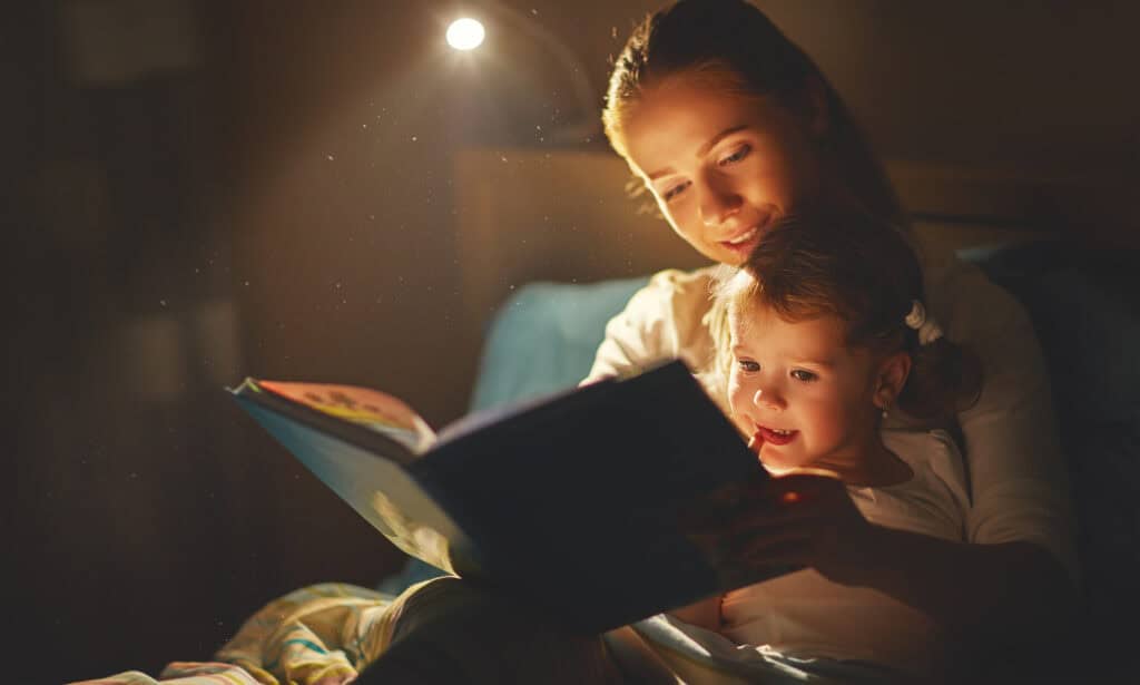 mother and daughter reading a book in bed before going to sleep - Children's Dental Center, Sioux Falls, SD