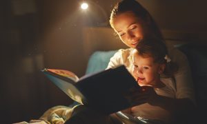 mother and daughter reading a book in bed before going to sleep